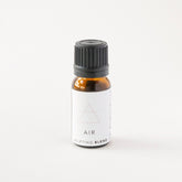 Small amber glass bottle of AIR essential oil blend on white bench.