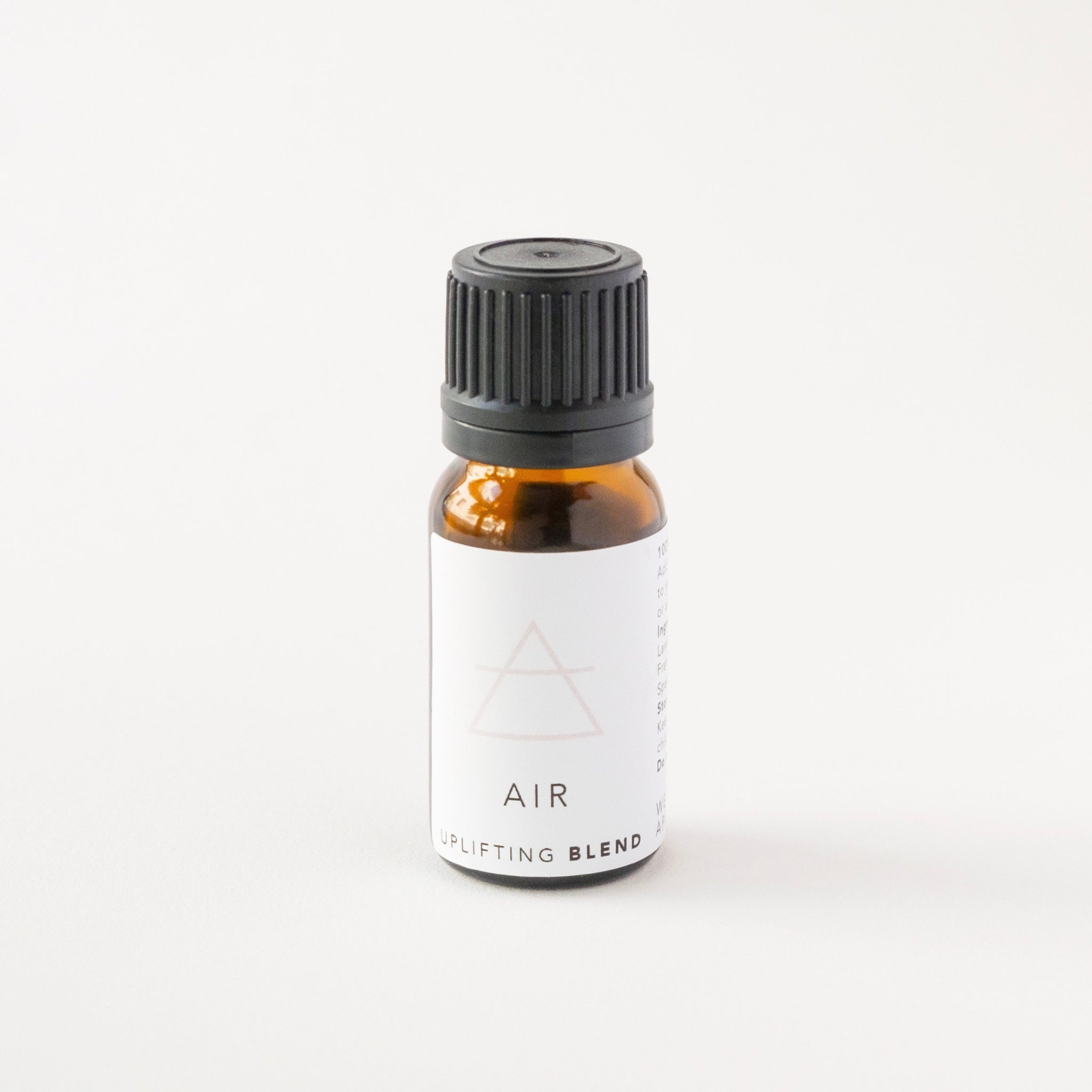 Small amber glass bottle of AIR essential oil blend on white bench.