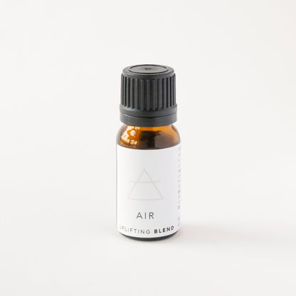 Small amber glass bottle of AIR essential oil blend on white bench.