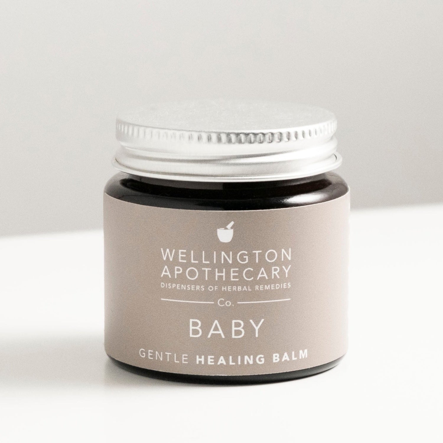 Amber glass jar of baby healing balm on white bench. 