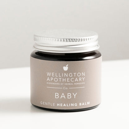 Amber glass jar of baby healing balm on white bench. 