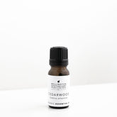 Small amber glass bottle of cedarwood essential oil on white bench. 