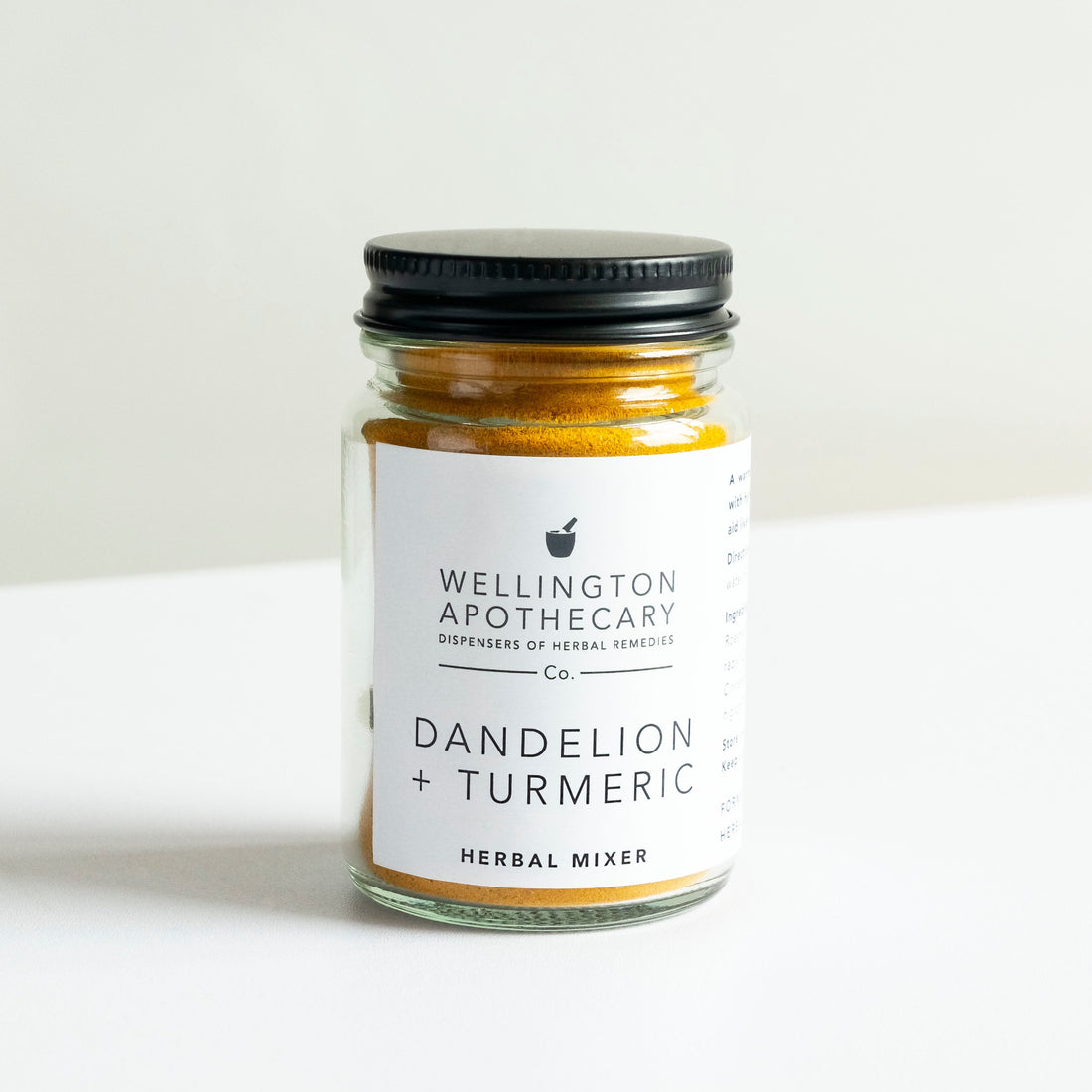 A glass jar of bright rich yellow turmeric and dandelion root herbal mixer.