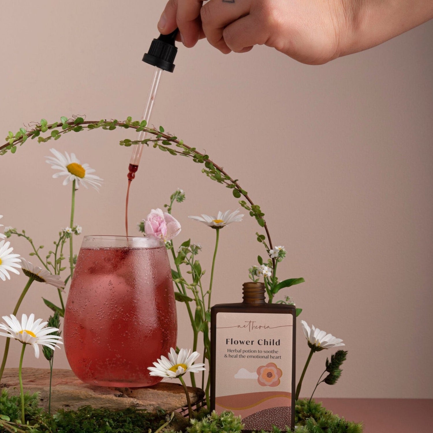 A bottle of Flower Child tonic being dropped into a glass of deep pink juice. 