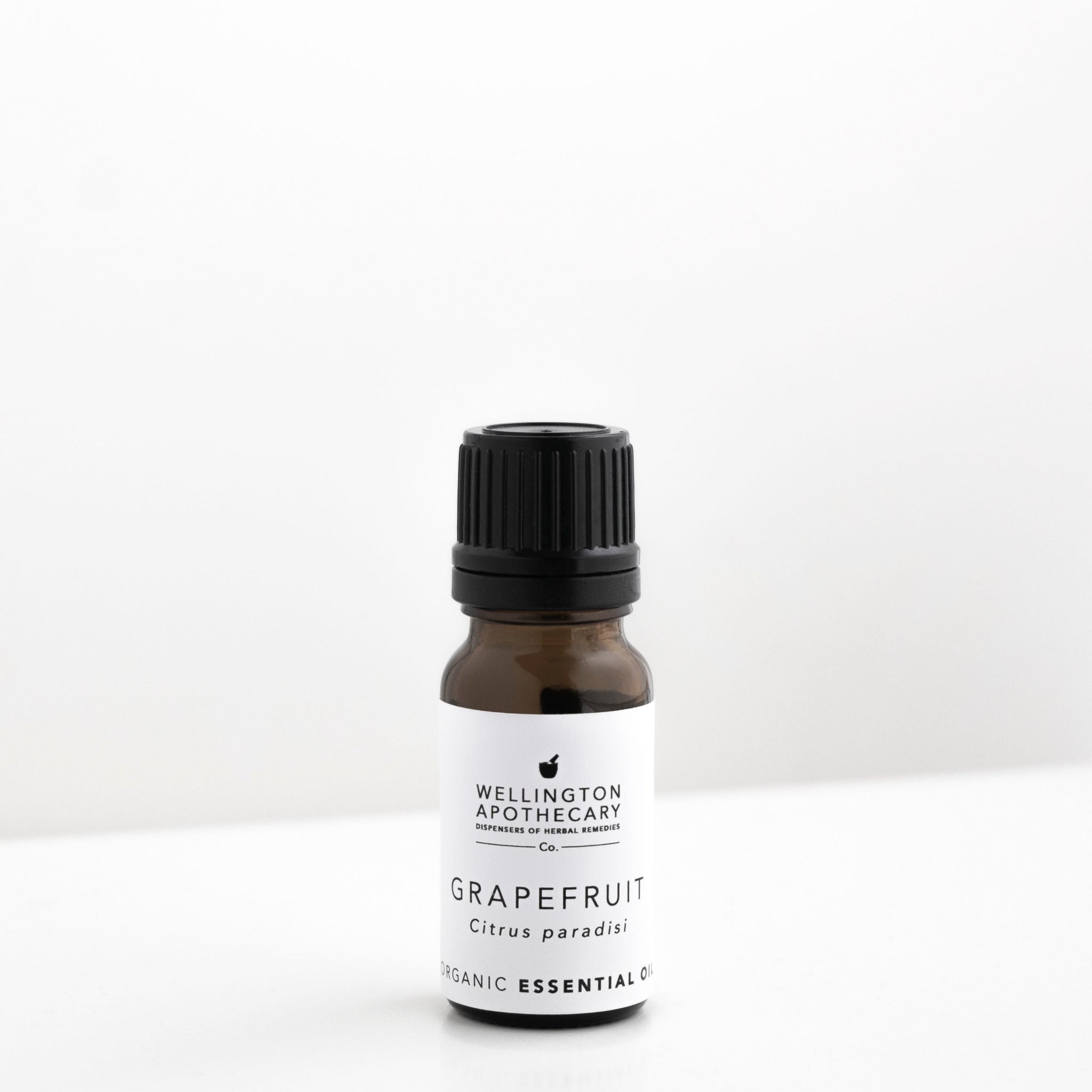 Smal amber glass bottle of grapefruit essential oil on white bench. 