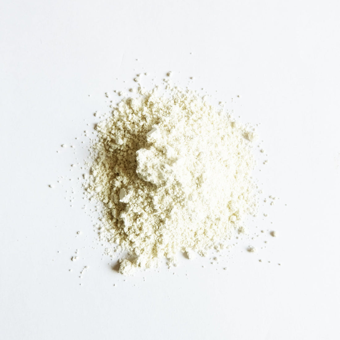 A pile of ivory clay powder on white surface.