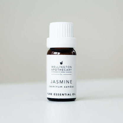 Small bottle of Jasmine essential oil on white bench with soft grey background. 