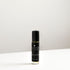 A small glass bottle of Juniper perfume oil blend on a white bench. 