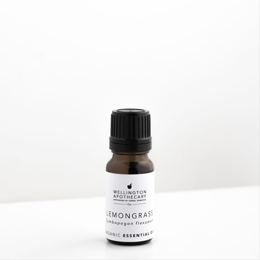 Small amber glass bottle of lemongrass essential oil on white bench. 