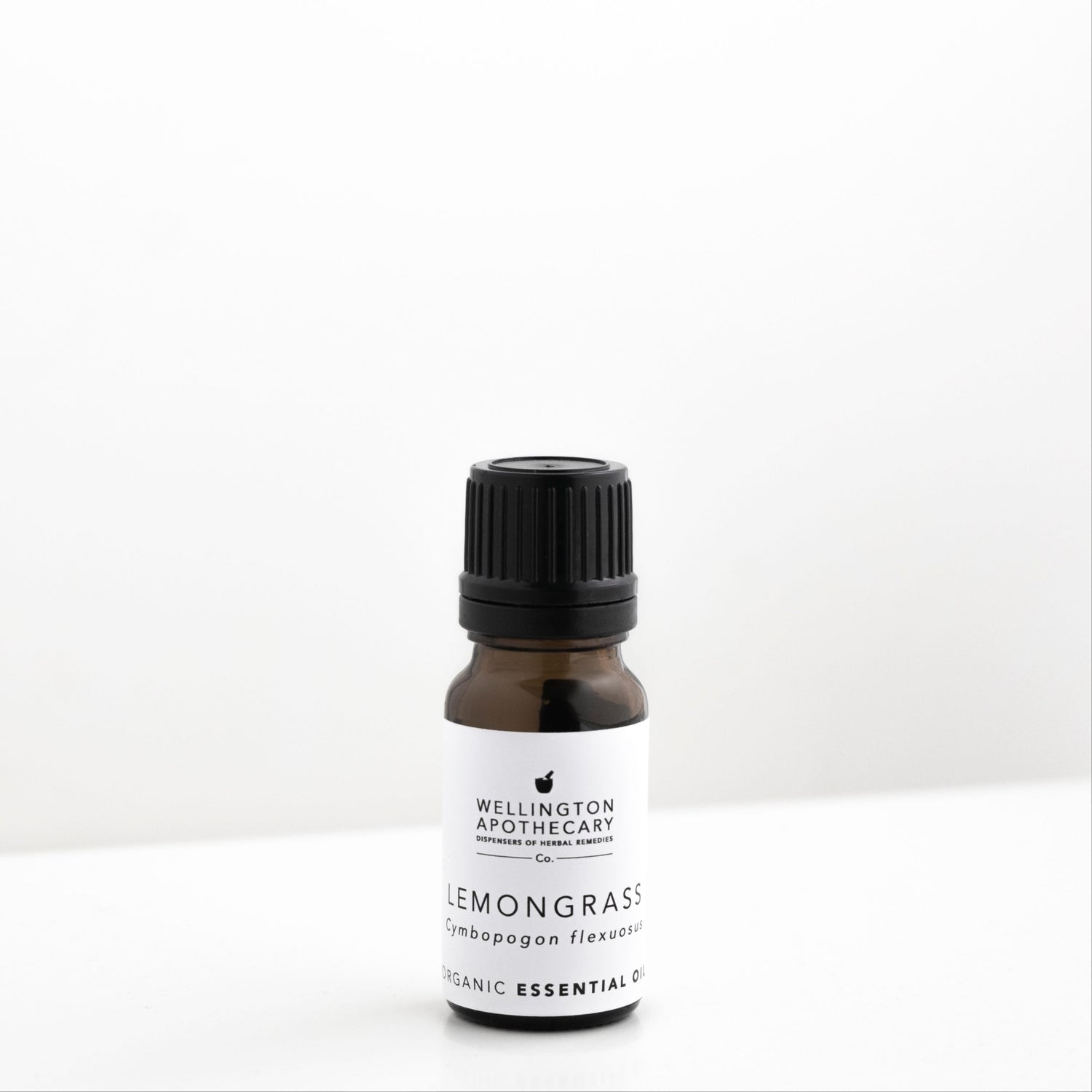 Small amber glass bottle of lemongrass essential oil on white bench. 