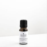 Small amber glass bottle of lemongrass essential oil on white bench. 
