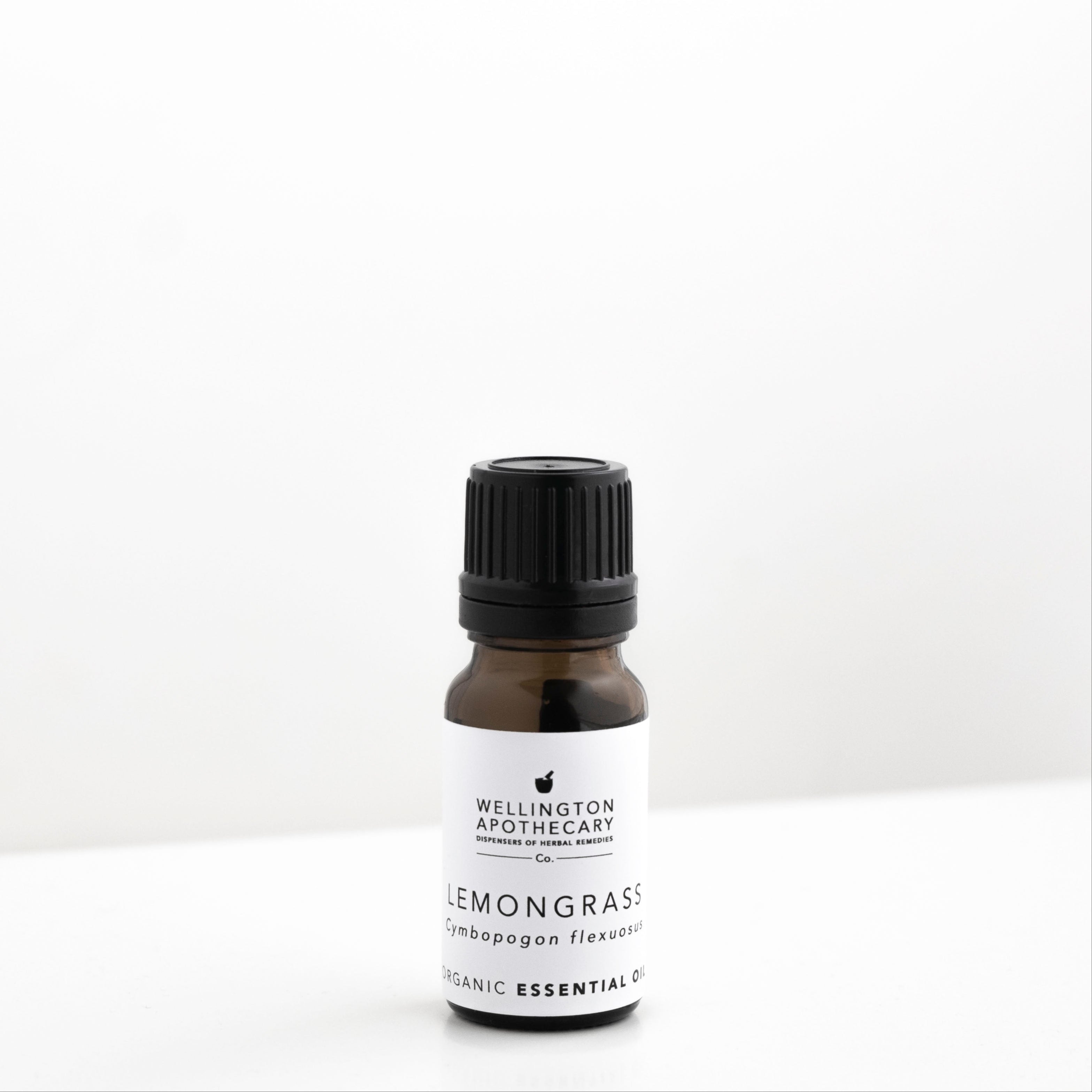 Small amber glass bottle of lemongrass essential oil on white bench. 