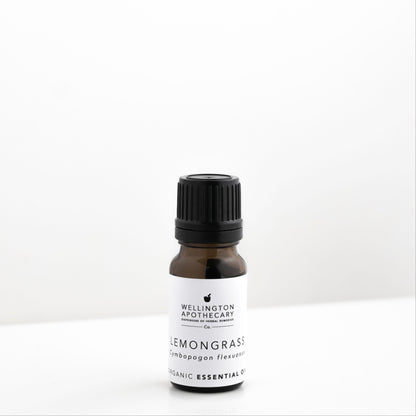 Small amber glass bottle of lemongrass essential oil on white bench. 