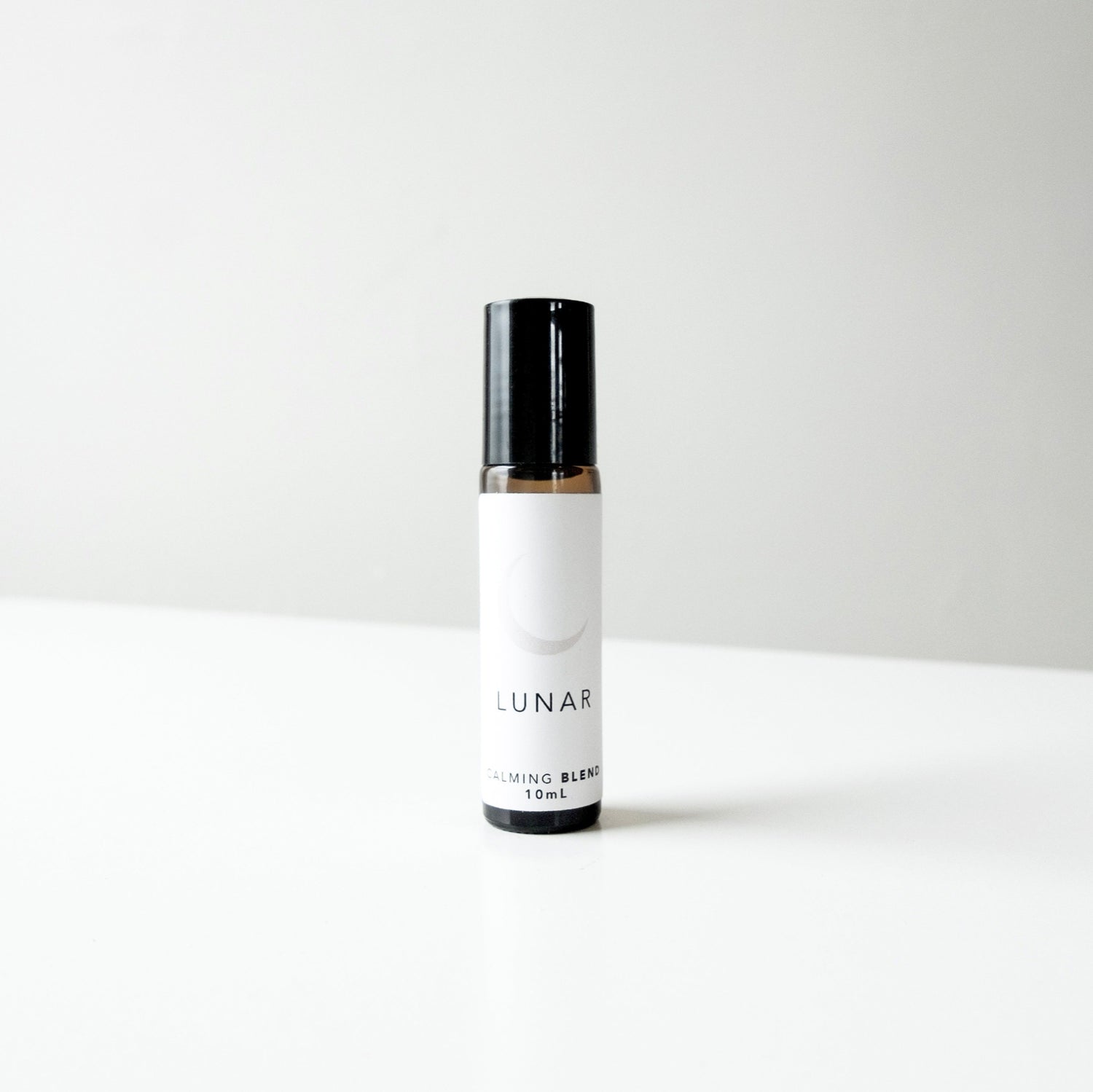 A small amber glass perfume bottle of lunar blend on a white bench. 