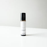 A small amber glass perfume bottle of lunar blend on a white bench. 