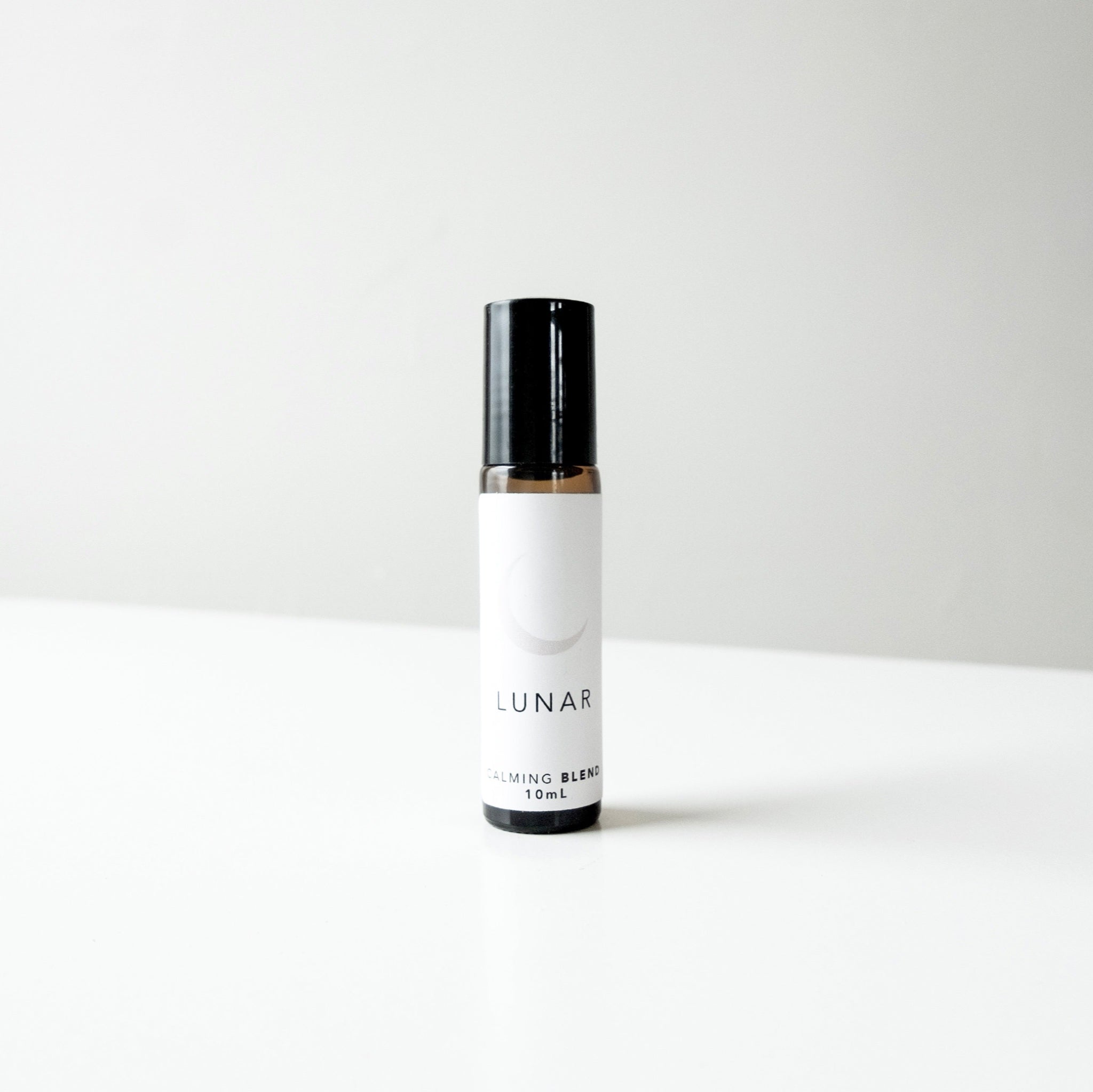 A small amber glass perfume bottle of lunar blend on a white bench. 