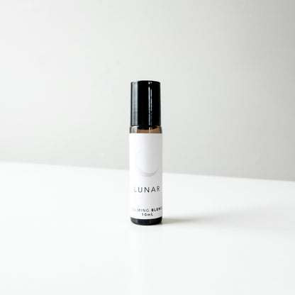 A small amber glass perfume bottle of lunar blend on a white bench. 