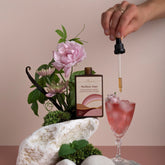 A bottle of Mellow Out tonic being dropped into a pink crystal glass.