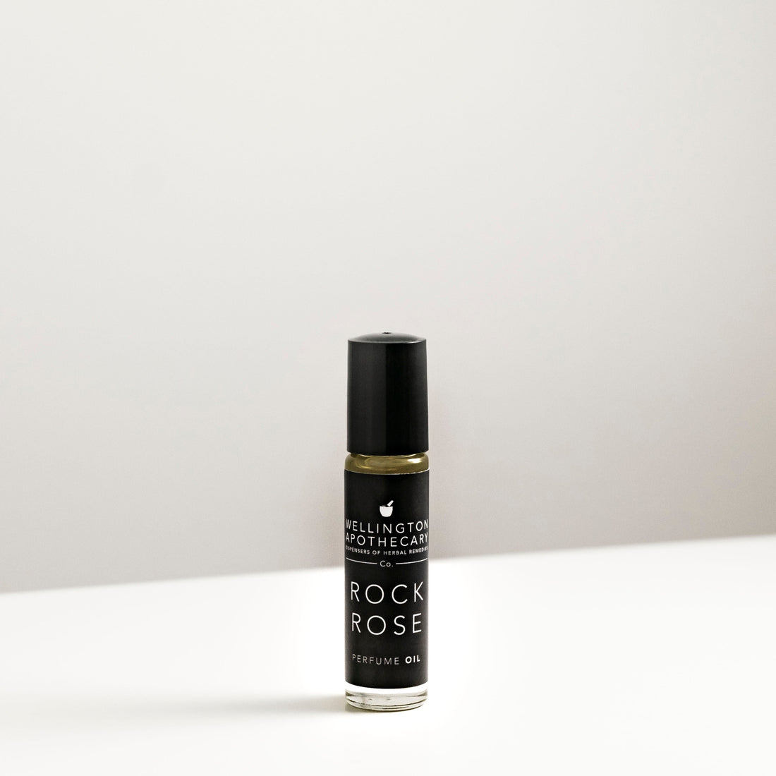 A small glass bottle of Rock Rose perfume oil on white bench. 