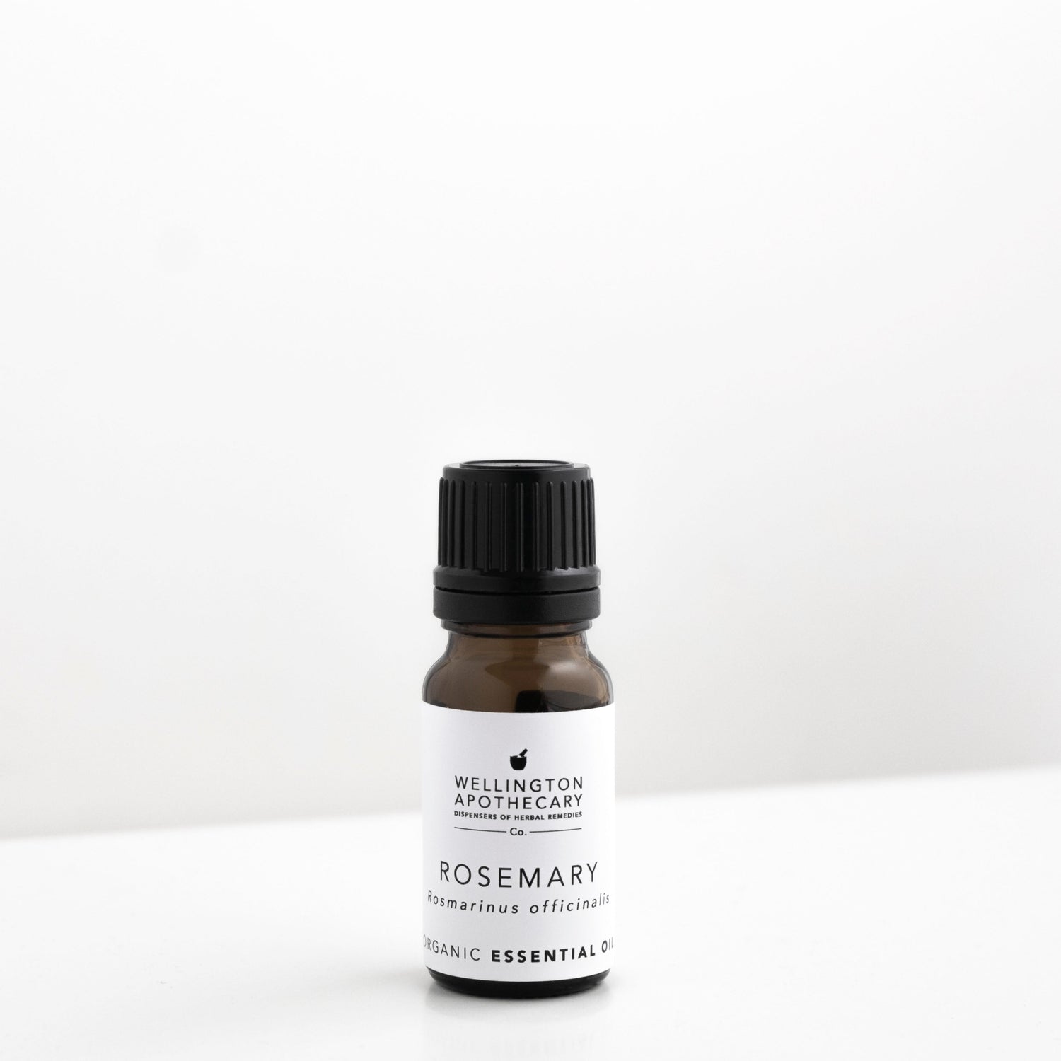 Small amber glass bottle of rosemary essential oil on white bench. 