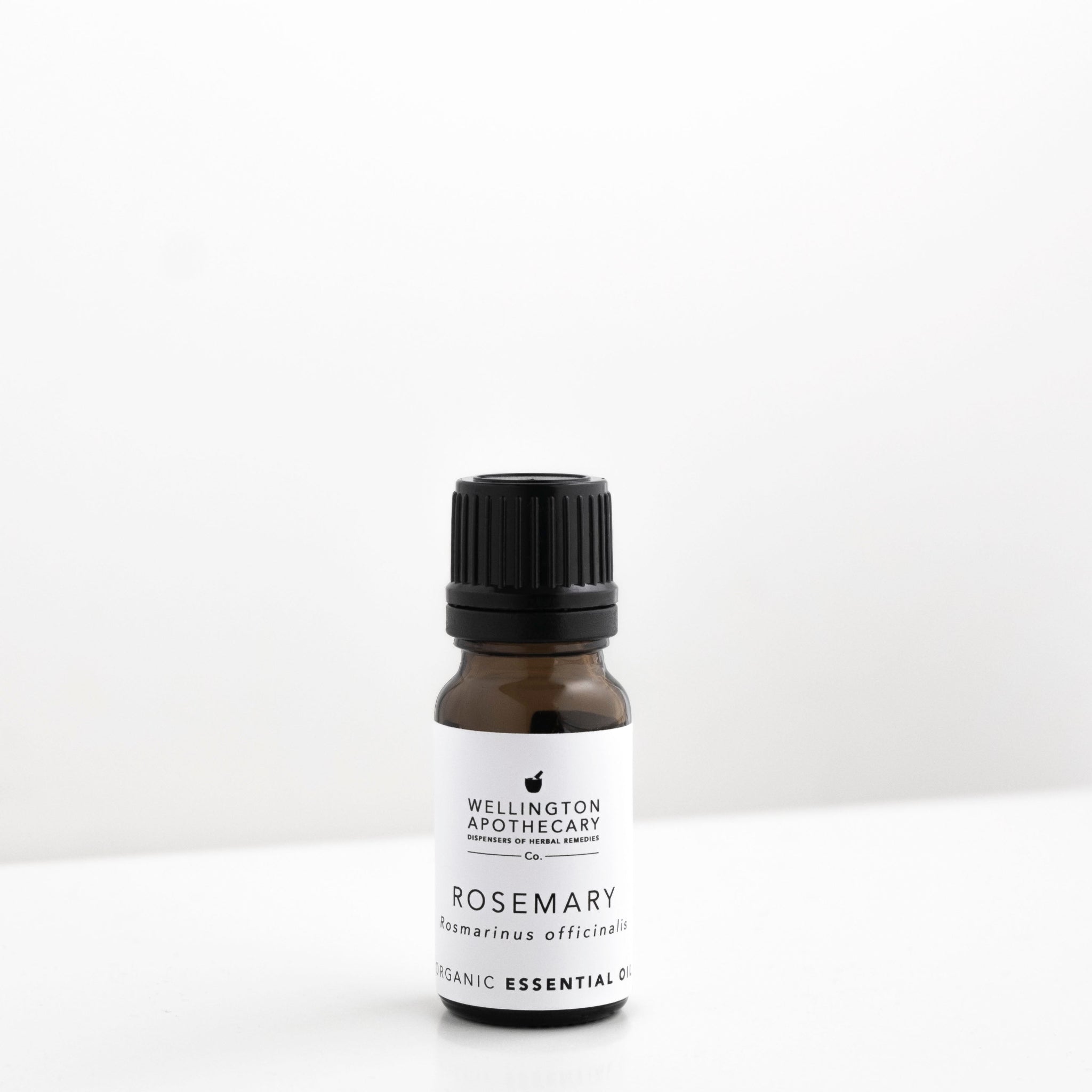 Small amber glass bottle of rosemary essential oil on white bench. 