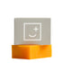 A mango coloured soap bar and grey box made by Fair + Square.