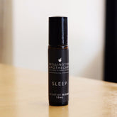 Amber glass roll on bottle of Sleep aromatherapy blend on wooden bench. 
