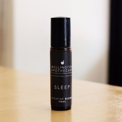 Amber glass roll on bottle of Sleep aromatherapy blend on wooden bench. 