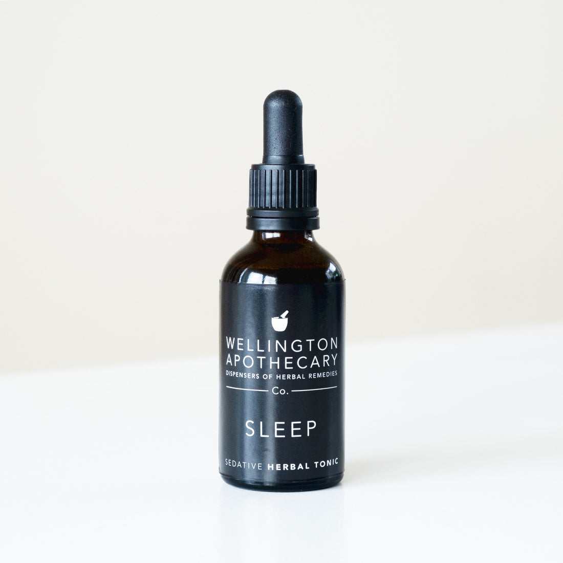 A black bottle of Sleep Sedative tonic on white bench. 