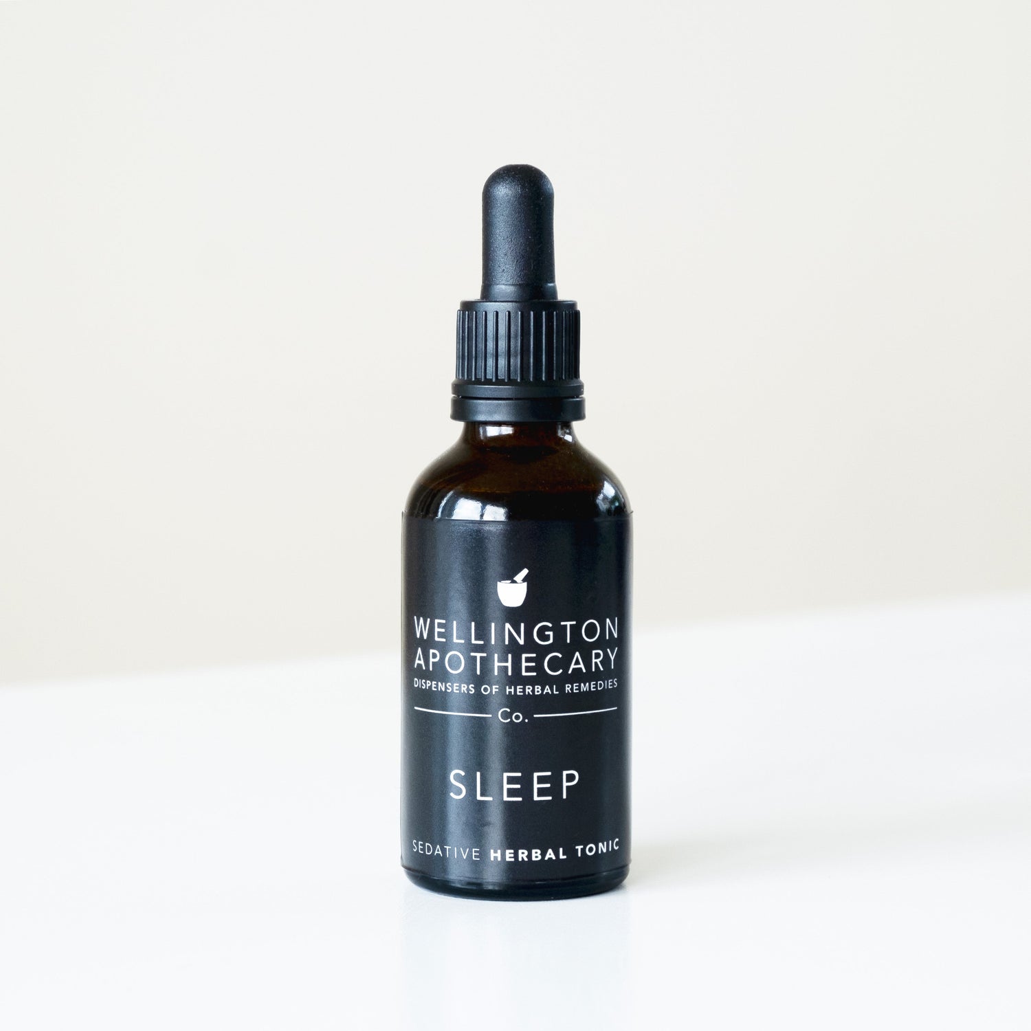 A black bottle of Sleep Sedative tonic on white bench. 