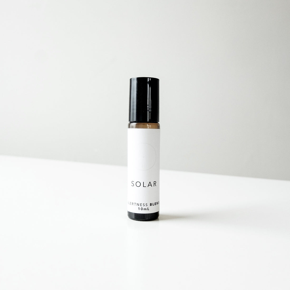 A small amber glass bottle of Solar perfume blend on a white bench.