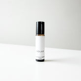 A small amber glass bottle of Solar perfume blend on a white bench. 