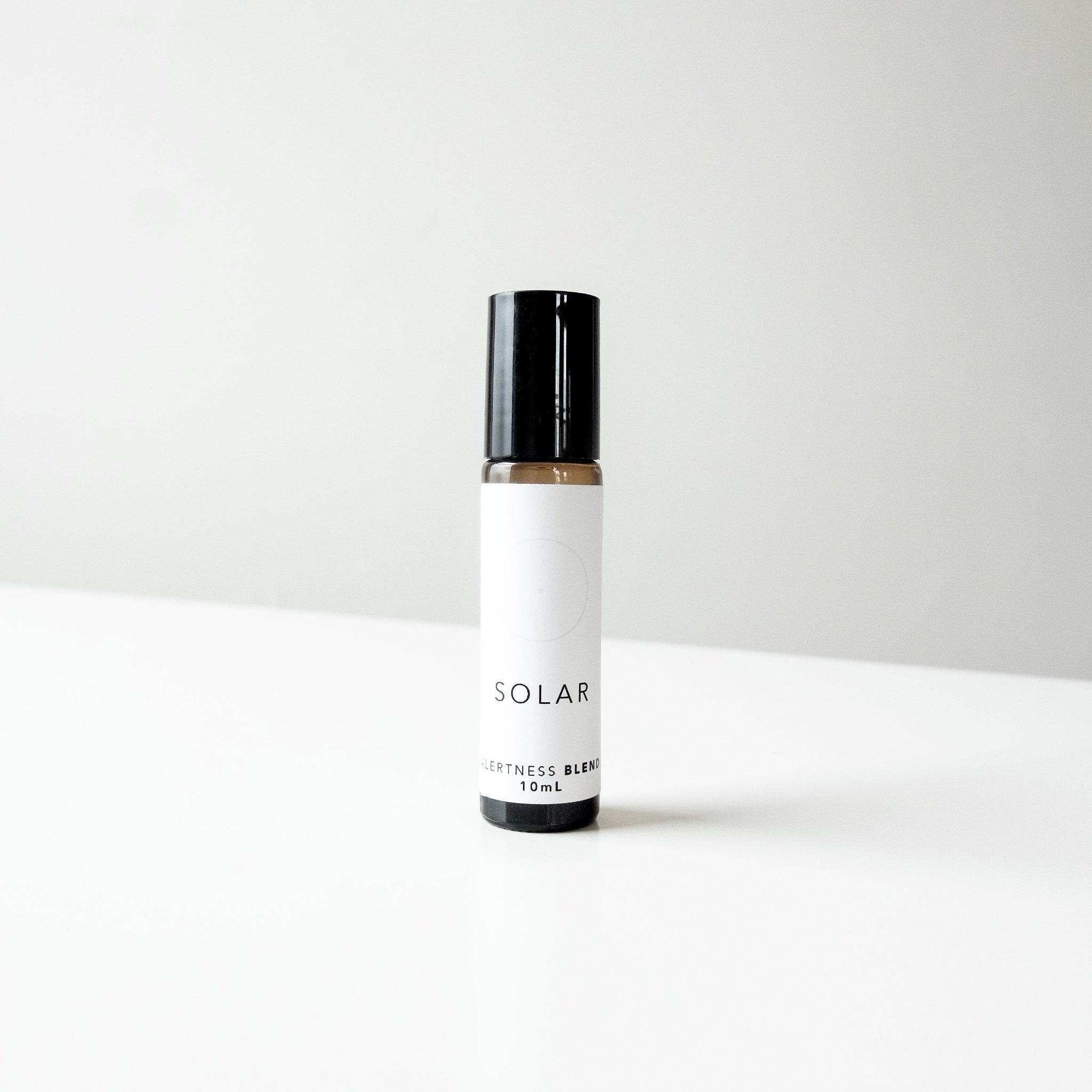 A small amber glass bottle of Solar perfume blend on a white bench. 
