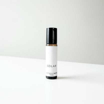 A small amber glass bottle of Solar perfume blend on a white bench. 