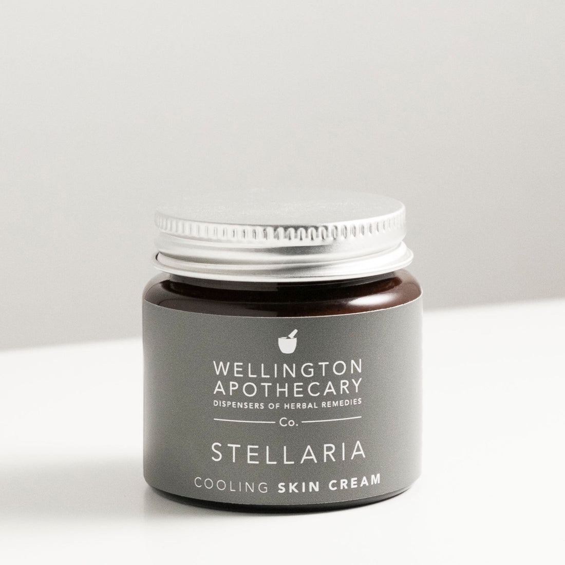 Amber glass jar of stellaria gel on white bench. 